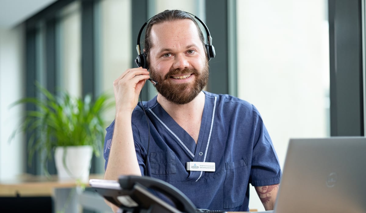 En man med hörlurar sitter framför en bärbar dator.